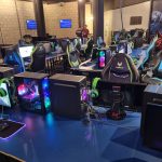 Ряд игровых мест с мониторами и игровыми креслами в компьютерном клубе